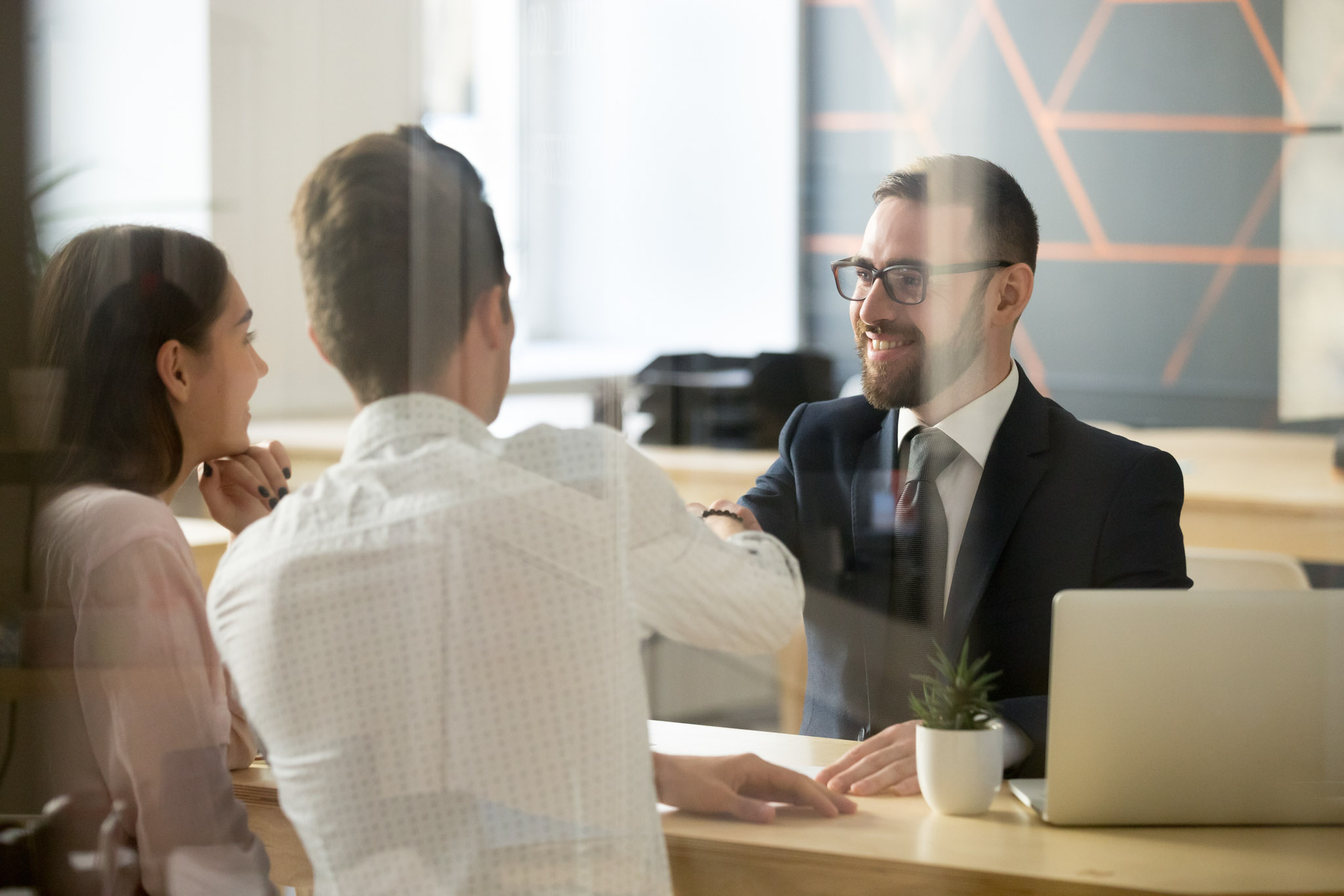 Male realtor handshaking clients after successful negotiations i